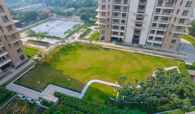 Alpha Gurgaon One — central lawn and tennis courts from above (real photo)