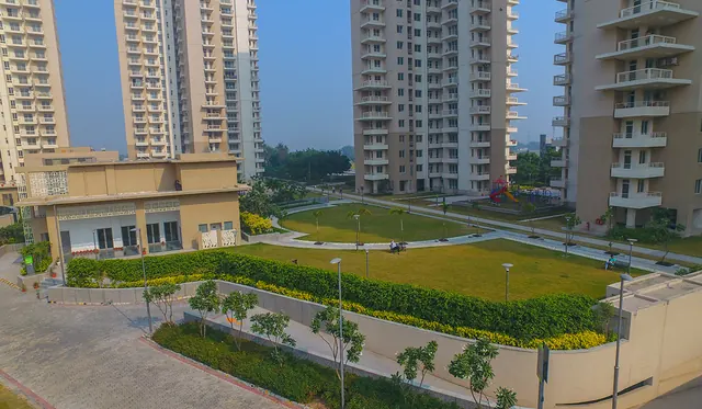 Alpha Gurgaon One — landscaped lawn with towers (real photo)