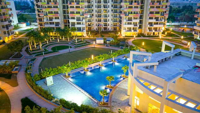 Bestech Park View Sanskriti — aerial of pool and clubhouse at dusk
