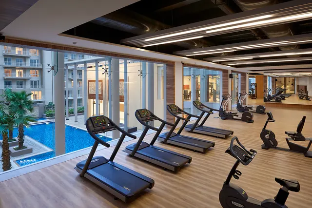 Puri Diplomatic Greens — gym overlooking pool (real photo)